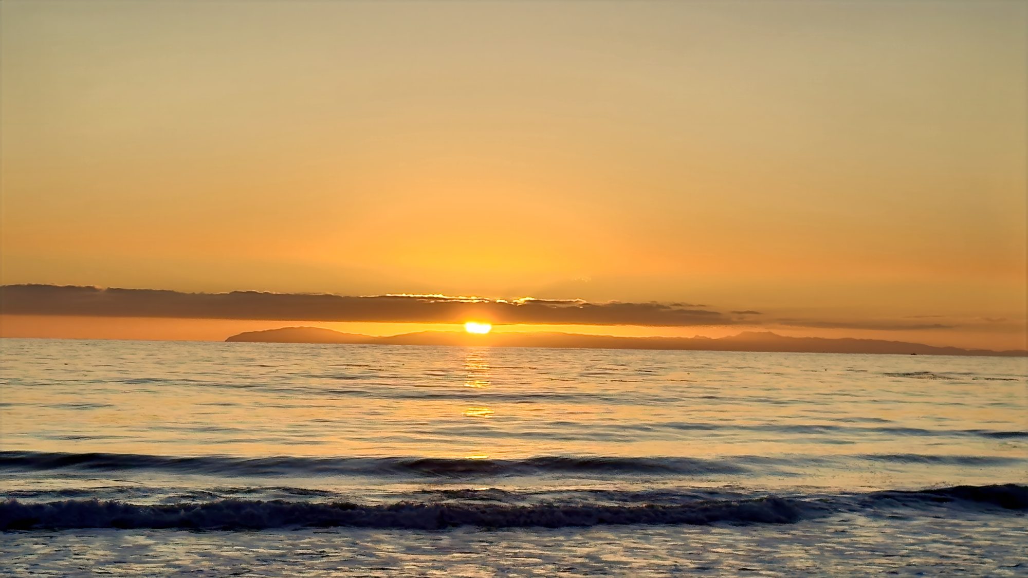 The sun low on the horizon over calm water, Corona del Mar